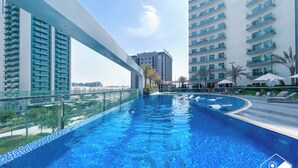 A modern hotel with a rooftop infinity pool, high-rise buildings, and a clear sky. - Urban Escape Studio Pool, Gym & Stylish Living (Dubai)