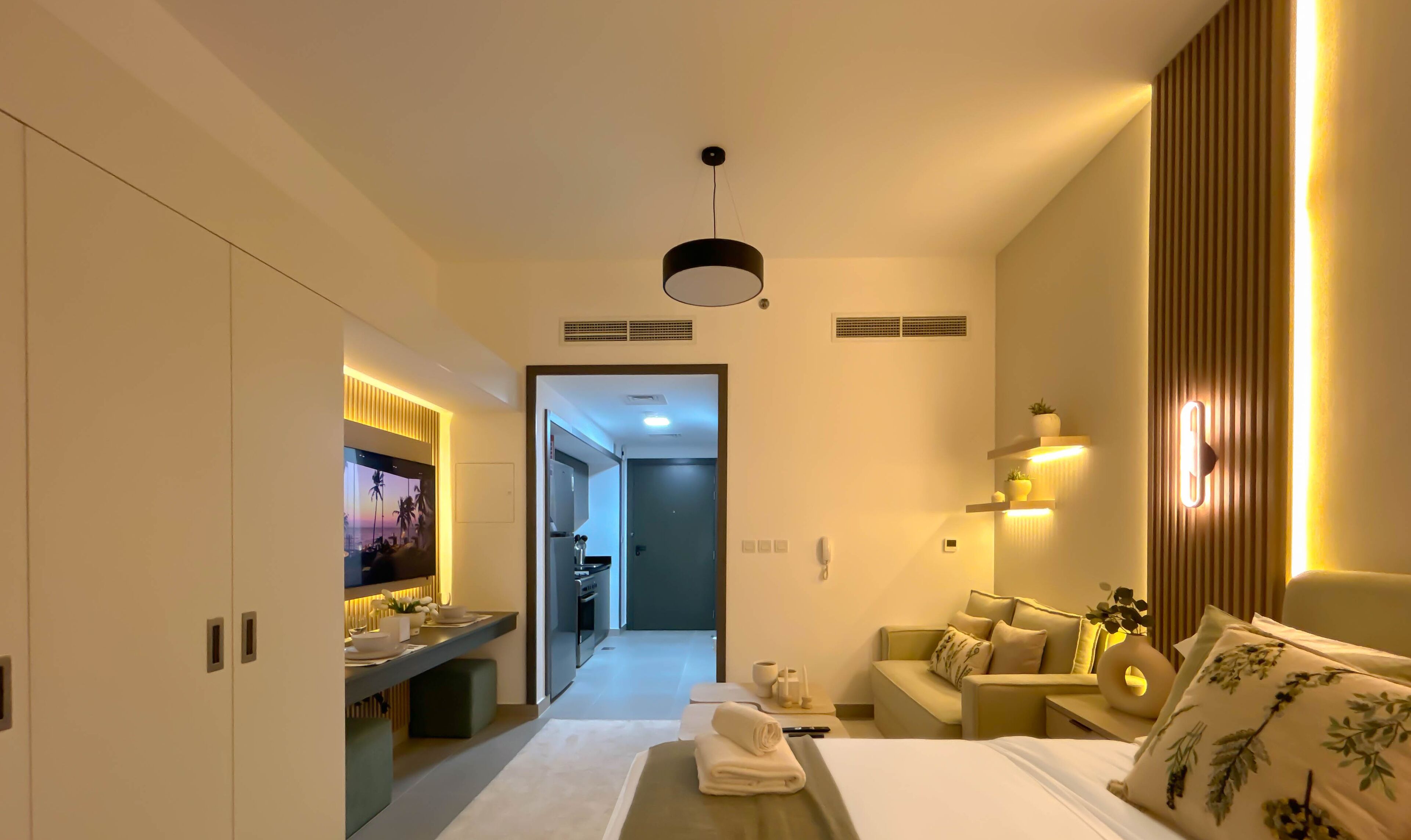A modern hotel room with a bed, a desk, a TV, and a bathroom.