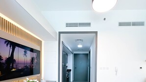 A modern hotel room with a dining area, a living area, and a hallway leading to the kitchen. - Urban Escape Studio Pool, Gym & Stylish Living (Dubai)