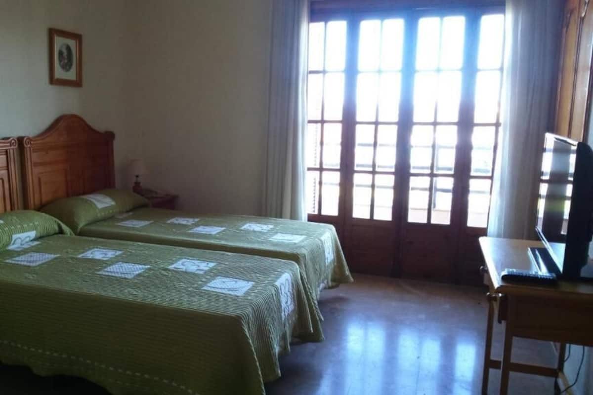 Ein Zimmer mit zwei Betten, einem Schreibtisch und einem Fenster mit Jalousien.