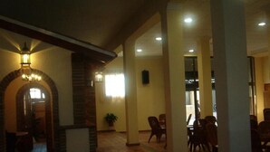 A spacious indoor area with a tiled floor, a stone fireplace, and several tables and chairs. - Hotel Luz del Guadiana (Ayamonte)