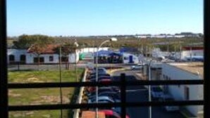 A parking lot with several cars, a building with a red roof, and a clear blue sky. - Hotel Luz del Guadiana (Ayamonte)