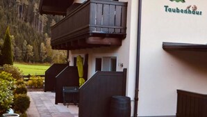 Un bâtiment sur lequel on peut lire l’inscription « Taubenhaus », et qui possède un balcon avec une balustrade en bois. On y trouve également une zone pavée avec un banc et une poubelle.