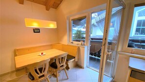 Une petite cuisine avec une table en bois et deux chaises, une fenêtre donnant sur l’extérieur et un luminaire au-dessus de la table.
