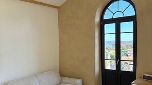 A living room with a sofa, a round table, and a black pendant light. - Roof top MARZE (Aubenas)