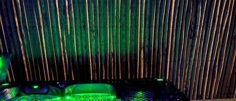 A room with a bamboo wall, a bed with a green-lit control panel, and a window.
