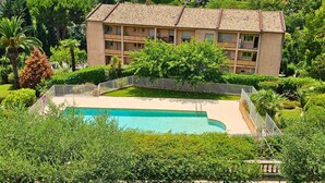 A multi-story hotel with a swimming pool surrounded by lush greenery and a fenced deck area. - Cosy apartment in Vence with swimming pool & parking (Vence)