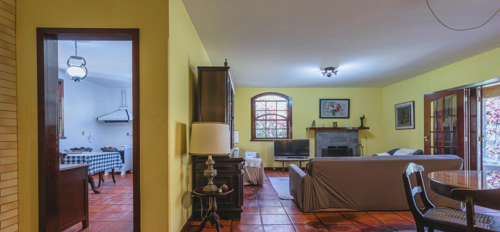 A living room with a sofa, TV, fireplace, and a dining area with a checkered tablecloth.