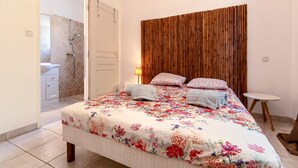 A bedroom with a bed, a wooden headboard, a bedside table, and a bathroom visible through an open door.