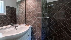 A bathroom with a white sink, a mirror, and a shower with a handheld showerhead.
