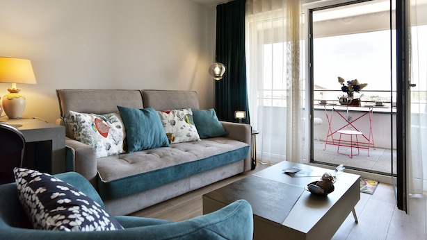A modern living room with a sofa, a coffee table, and a dining area with a balcony view. - Horizon Dinardais - Proche Plages (Dinard)
