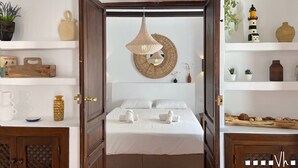 A bedroom with a bed, bedside tables, a hanging light fixture, and shelves with decorative items.
