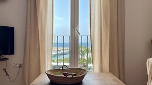 A room with a large window, a television on the wall, and a table with a basket.