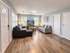 A living room with a dark-colored sofa, a lighter-colored sofa, a wooden coffee table, and a flat-screen TV on a stand. - Perfect Two Bedrooms with Fenced Yard and Three Blocks to Beach (Myrtle Beach)