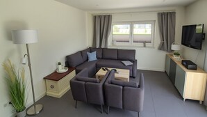 A modern, compact living space with a sofa set, a coffee table, a TV, and a lamp.