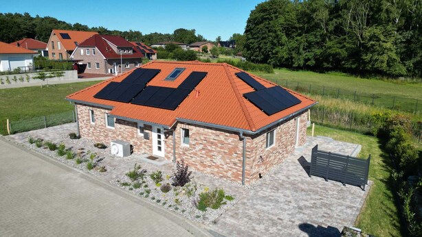 A single-story brick building with a red-tiled roof and solar panels.