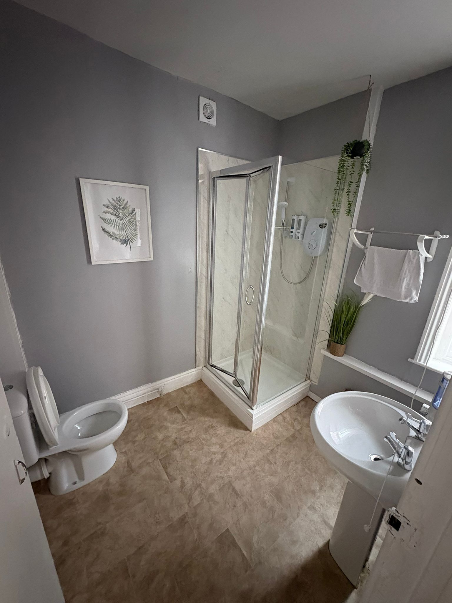 A bathroom with a toilet, shower, and sink.
