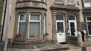 A corner building with a ground-floor shop and upper-floor residential units.
