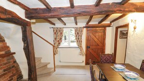 A dining area with a wooden table, chairs, and a rustic staircase.