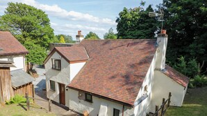 A traditional house with a red-tiled roof, white walls, and a chimney.