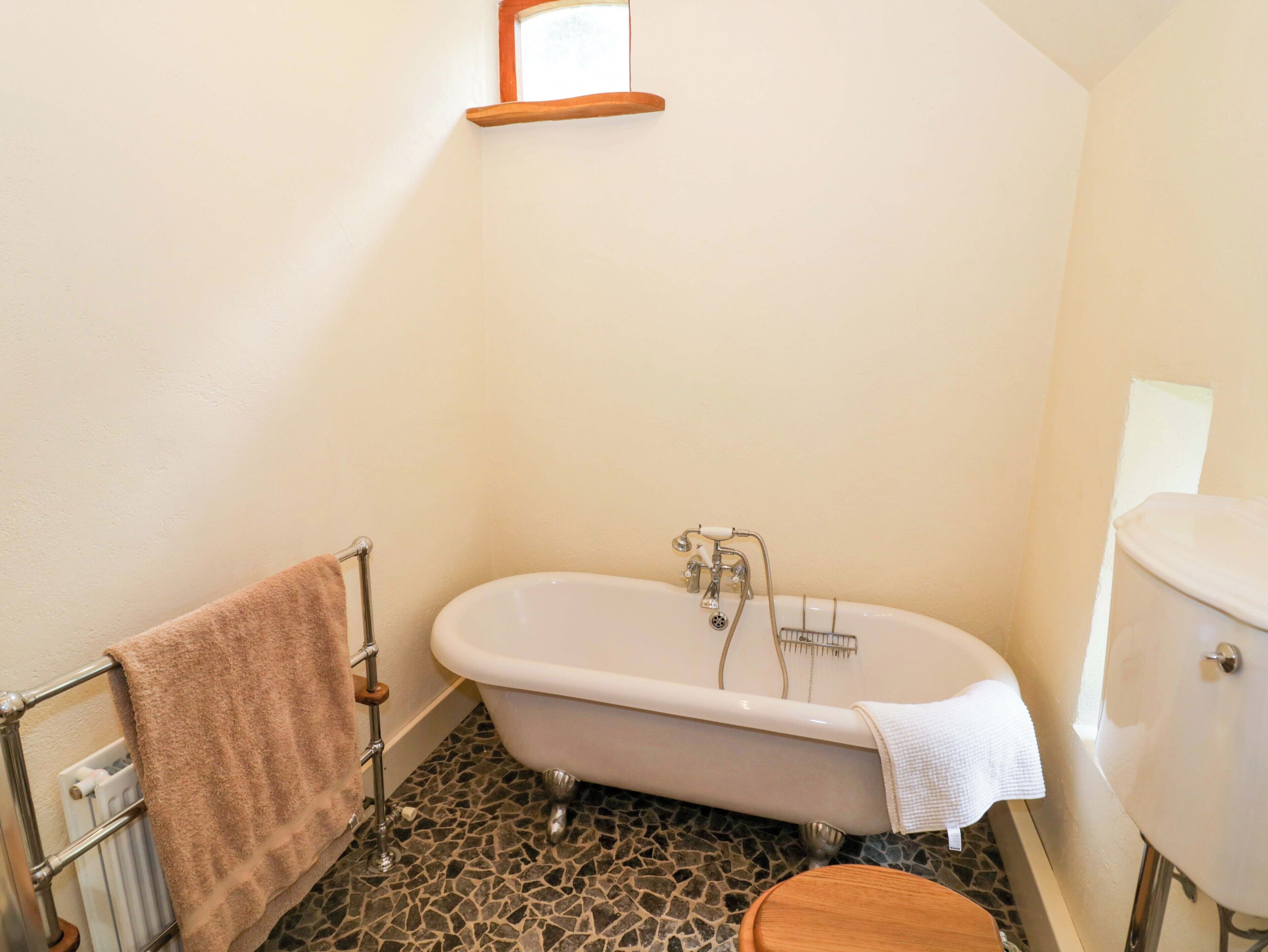 A bathroom with a freestanding bathtub, a toilet, and a radiator.