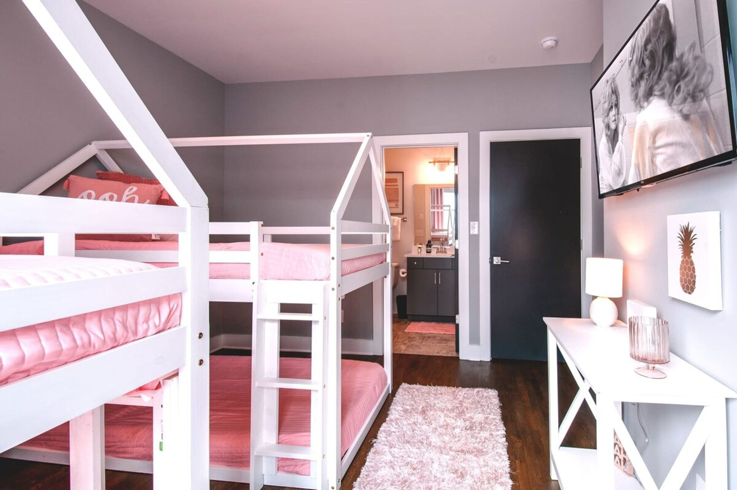 A bedroom with bunk beds, a desk, and a TV.