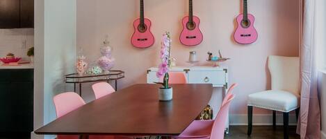 A dining area with a wooden table, pink chairs, and a white furry rug.