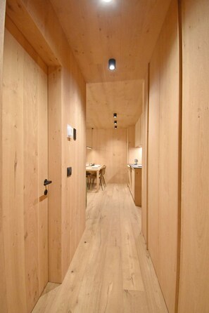 A narrow wooden hallway with a dining area at the end. - CACCIATORA Alpine Apartment MhD (Madonna di Campiglio)