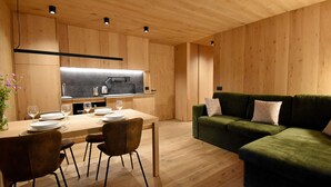 Una cocina moderna con armarios de madera, una mesa de comedor con sillas y un sofá verde.