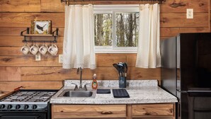 A kitchen with wooden walls, a granite countertop, a stove, a sink, and a refrigerator.