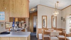 Una cocina compacta con armarios de madera, un lavamanos y una zona de comedor con candelabro.