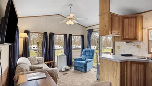 Interior compacto de una caravana con kitchenette, zona de comedor y área de estar con una silla azul.