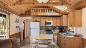 A cozy kitchen with wooden cabinets, a dining table, and a built-in microwave. - Vacation Home Rental PM 51 (Russell)