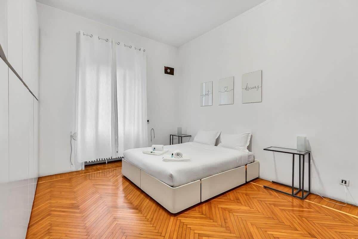 Une chambre à coucher moderne avec un grand lit, une table de chevet et une petite table d’appoint.