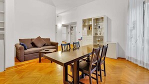 Un salon moderne avec un plancher en bois, un canapé marron, une table à manger avec des chaises et une étagère blanche.