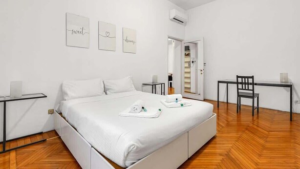 Une chambre à coucher moderne avec un lit, des tables de chevet, un bureau et une chaise.