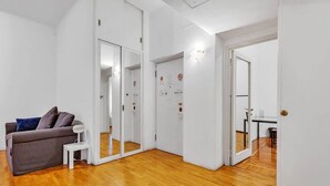 Un appartement moderne avec un plancher en bois, un canapé gris et une petite table blanche.