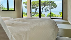 Un dormitorio con una cama grande, una ventana y vistas a árboles y agua.