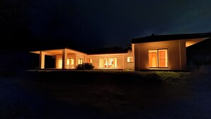 Una casa moderna de dos pisos con un porche cubierto y amplias ventanas.