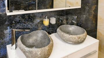 Un baño con dos lavamanos de piedra, un espejo grande y un salpicadero de mármol.