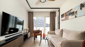 A modern living room with a flat-screen TV, a sofa, a coffee table, and a chair.