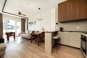 Una cucina moderna con mobili in legno, un'area pranzo con tavolo e sedie e un soggiorno con divano e tavolino.