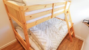 Una cama litera con estructura de madera y ropa de cama blanca.