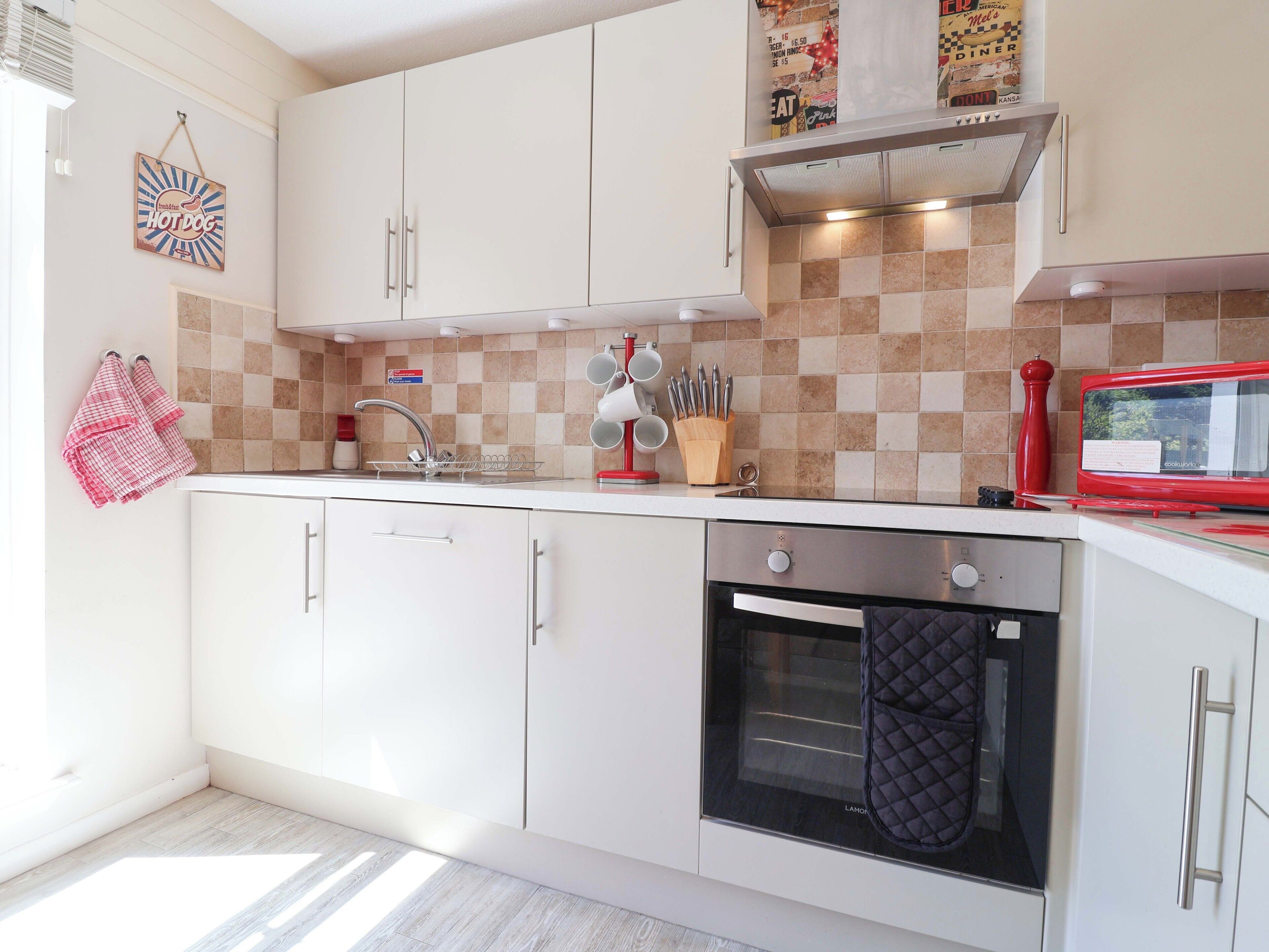 Eine moderne Küche mit weißen Schränken, einem eingebauten Backofen, einer Mikrowelle und einer karierten Spritzschutzwand.