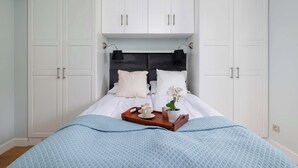A bedroom with a bed, white wardrobe, and a tray with a cup and a flower.