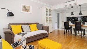 A modern living room with a sofa, ottoman, and dining area with chairs and a table.