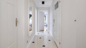 A hallway with white doors, a tiled floor, and a ceiling light.