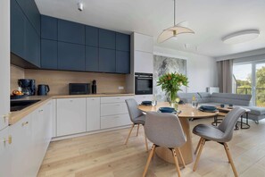 Cozinha moderna com armários escuros, bancada de madeira e área de jantar com mesa e cadeiras redondas.