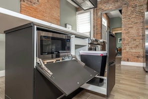 A modern kitchen with a built-in microwave, a small refrigerator, and a sleek countertop.