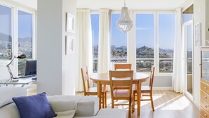 Una sala de estar moderna con comedor, ventanas amplias y vista a la ciudad.
